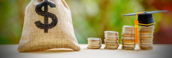 A concept photo of student debt is shown via a dollar bag and a graduation cap on a row of coins on a table.