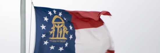 A flag of the U.S. state of Georgia is seen waving on a flagpole.