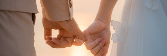 The bride and groom use the little finger together. lovely couple hold hand with sunset background