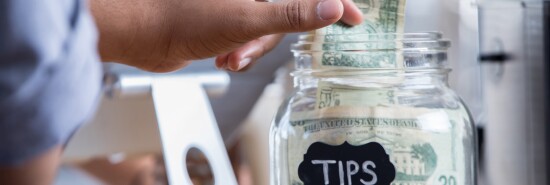 Customer places cash in a tip jar 0