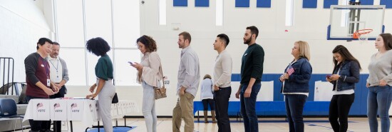 Group of people wait in long line in polling place