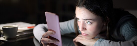 Worried woman checking smart phone in the dark night