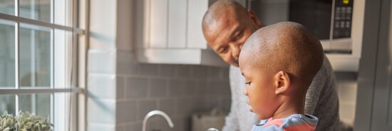 Father and child cleaning at home. A mature man and his son washing dishes. Family with a little boy learning to do chores in the kitchen