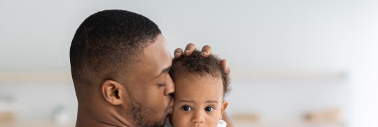 Father's Care. Young Black Dad Holding And Kissing Adorable Newborn Baby