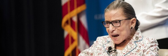 Supreme Court Associate Justice Ruth Bader Ginsburg gestures as the invited guests applaud while she gets seated at Georgetown University Law Center in Washington.