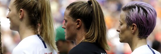 United States' Megan Rapinoe, right, and her teammates listen to their national anthem prior the Women's World Cup final soccer match between US and The Netherlands at the Stade de Lyon in Decines, outside Lyon, France.