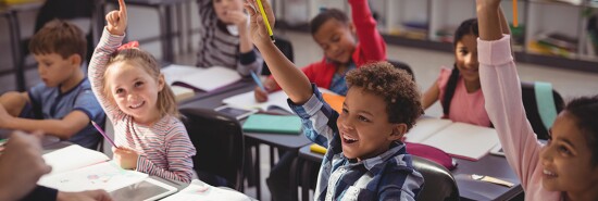 Students in a classroom raising their hands.