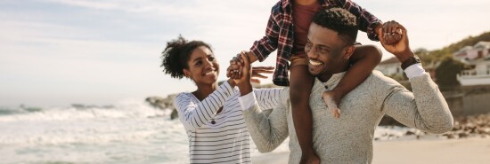 Parents carrying son on shoulders on beach vacation