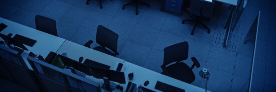 Elevated High Angle Shot of Dark Empty Office with Wheelchairs, Desks and Computers. Concept of Finishing Working Alone Late at Night.