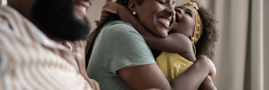 Cute girl embracing mother at home