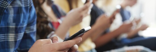 Close Up Of A Line Of High School Students Using Mobile Phones